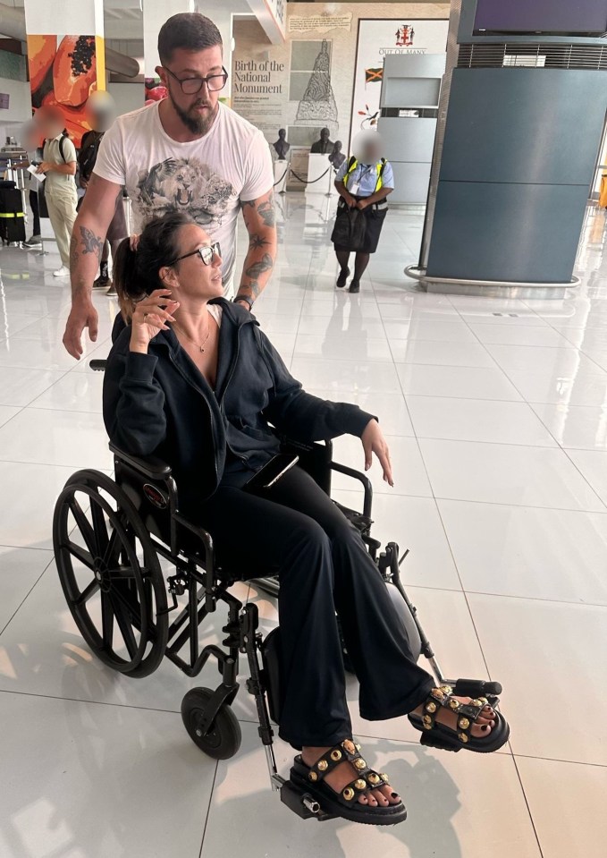 Woman in wheelchair at airport with a man assisting her.