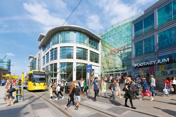 Manchester Arndale with shoppers walking outside along high street and yellow tram on road