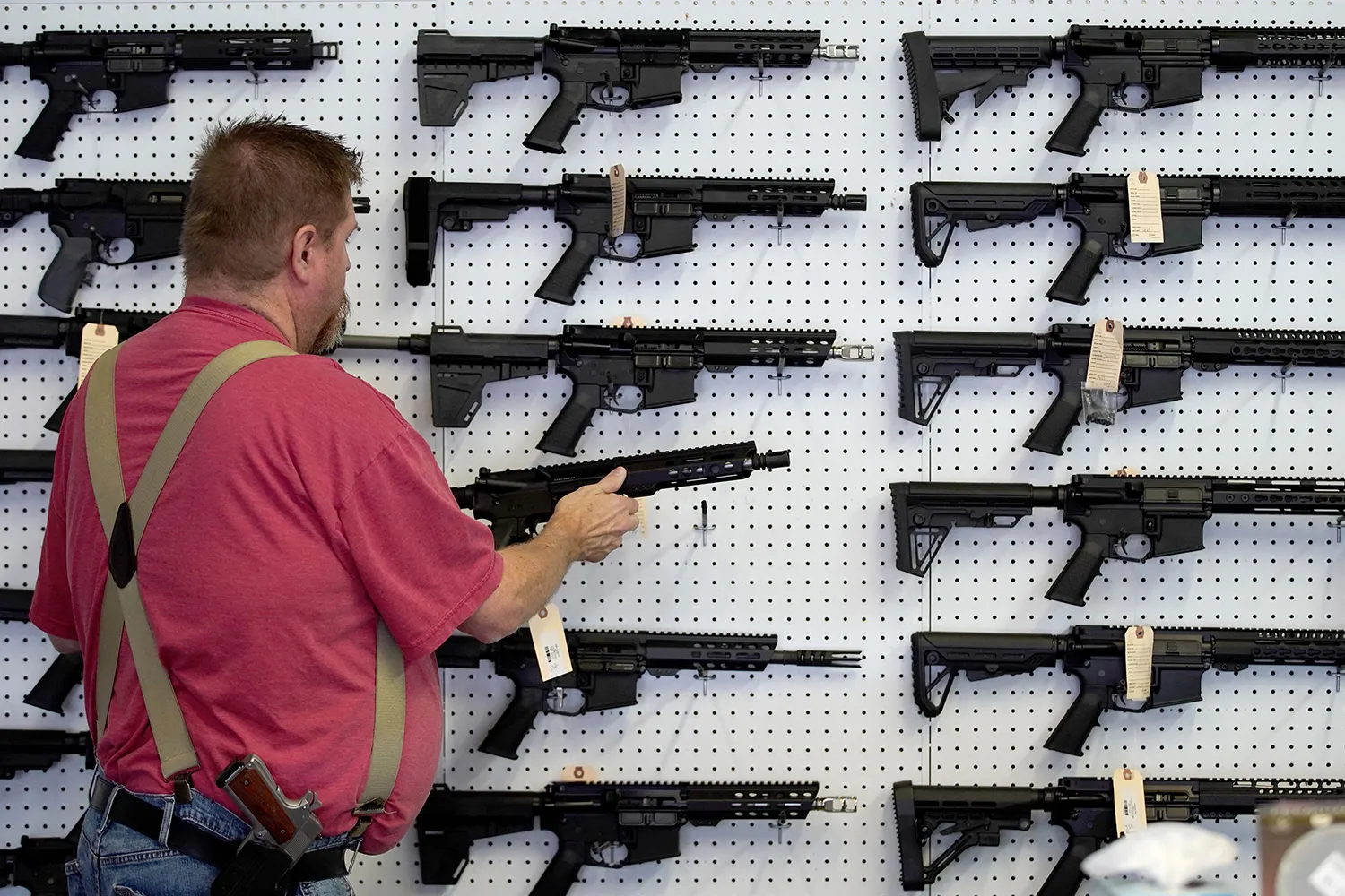 A worker restocks a wall full of AR-15 guns.