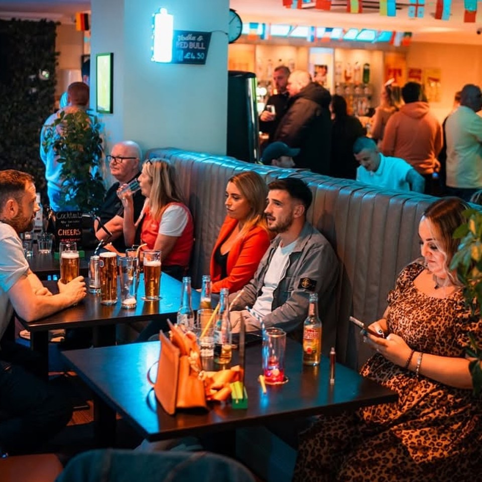 Patrons sitting at tables in a bar.