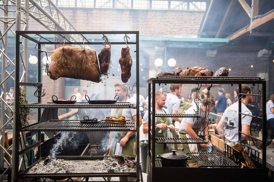Large outdoor barbecue with meats hanging and cooking on racks.