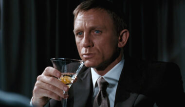 Daniel Craig somberly drinks a martini at a dimly lit airplane bar in Quantum of Solace.
