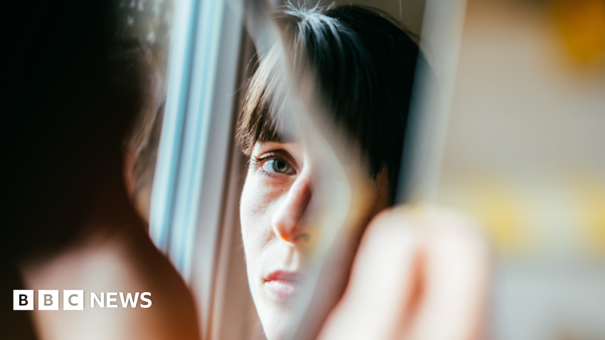 Young woman looks into a broken mirror