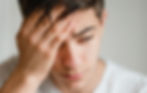 Young man rubbing his head while looking stressed
