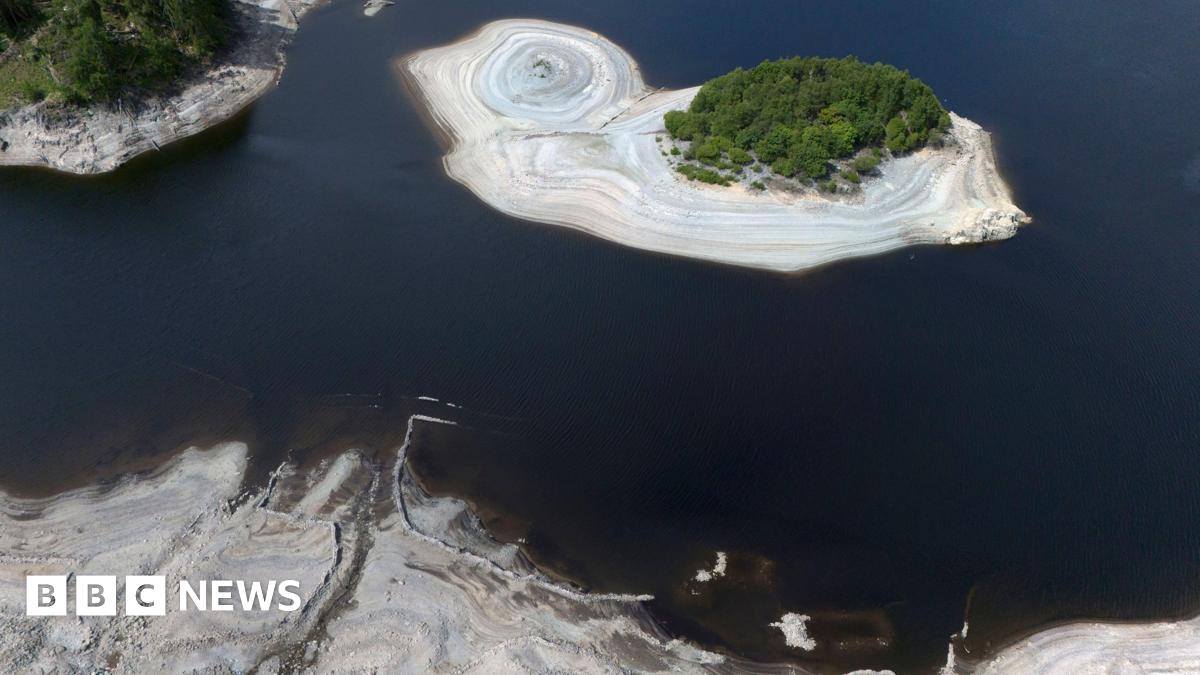 An aerial view of Haweswater reservoir, which shows receding water levels exposing light brown silt-beds.