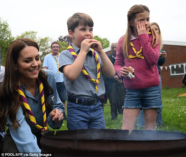 Pictured: Britain's Princess Charlotte of Wales (R) wipes her eyes as she and her brother Britain's Prince Louis of Wales (C) eat marshmallow biscuits as they take part in the Big Help Out, during a visit to the 3rd Upton Scouts Hut in Slough, west of London on May 8, 2023