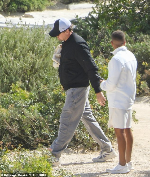 Leo wore a black bomber jacket over a white t-shirt with grey cargo pants. His ever-present ball cap and sunglasses helped to disguise his famous face