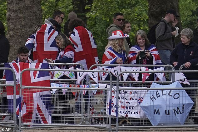 People wearing British flags take their place along the Mall as they await the anniversary parade