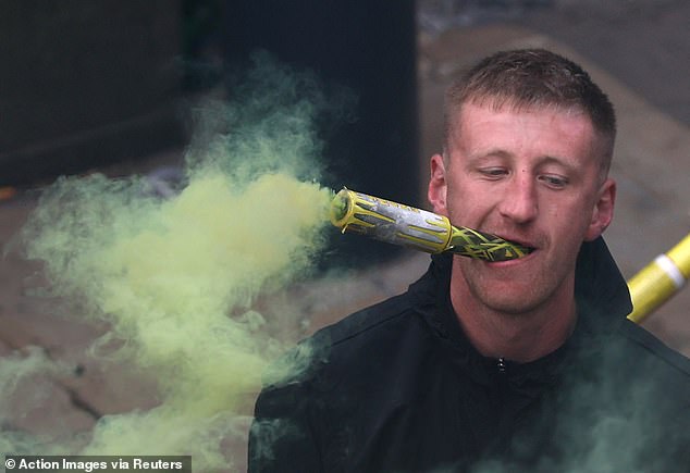 This Leeds fan holds a flare in his mouth to imitate smoking a cigar during the wild scenes