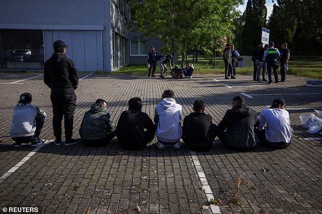 Suspected illegal migrants sit on the ground after they were detained by German police during their patrol along the German-Polish border to prevent illegal migration, in Forst, Germany, September 20, 2023