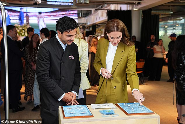 Kate grinned as she viewed rings designed by Bleue Burnham (left), at the event in London this afternoon