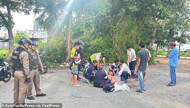 The British ex-convict was already covered in blood when the driver dragged him out of the backseat and dumped him onto the pavement before allegedly stabbing him and fleeing the scene. Pictured: Mr Cook, still conscious, receiving treatment from paramedics at the scene