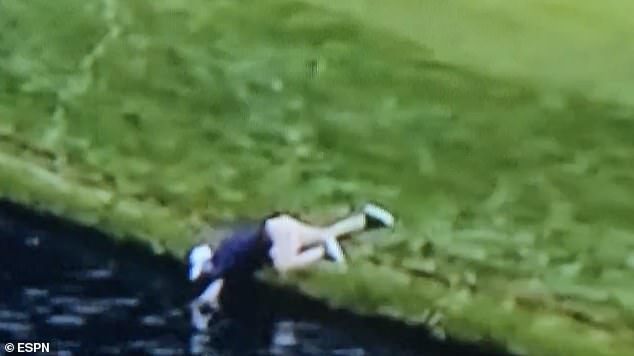 The volunteer reached so far into the water his torso was nearly in the lake by the 14th green