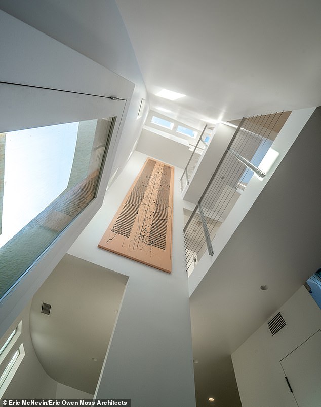 The home is organized around a dramatic central atrium, with bridges crossing at each level