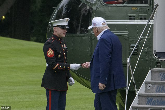 President Donald Trump, right, gives a challenge coin to a U.S. Marine as he disembarks Marine One upon arrival on the South Lawn