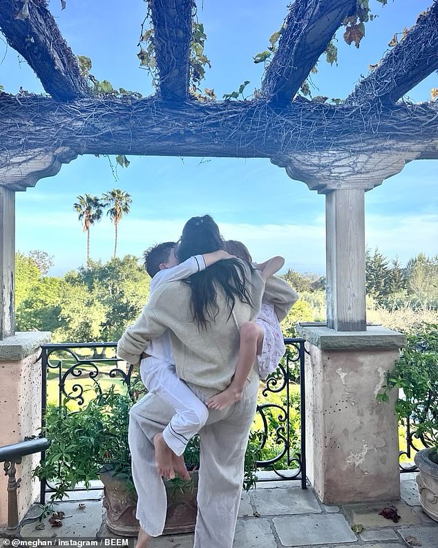 Meghan, pictured at home being climbed on by her children Archie and Lilibet on Mother's Day, is said to be 'distant'  and has 'never tried to fit in' in Montecito, a journalist and neighbour has claimed