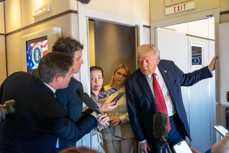 Donald Trump leans over to talk to the press in Air Force One.