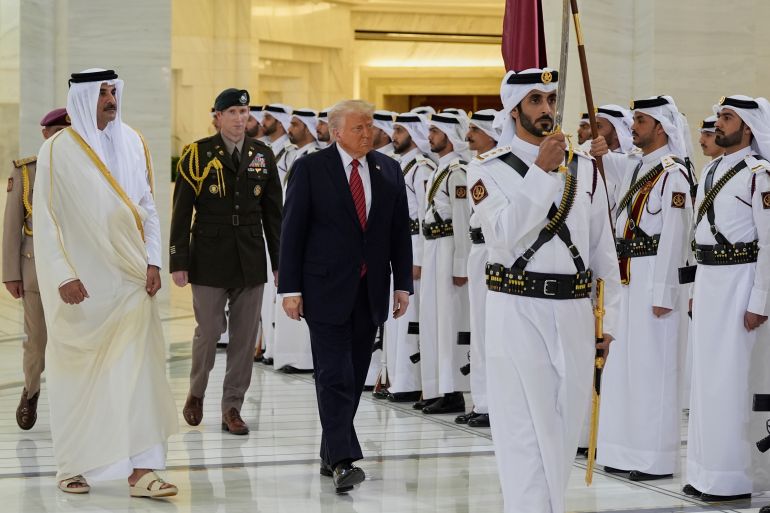 Trump walks with Emir Sheikh Tamim bin Hamad Al Thani as guard with a sword leads the way.