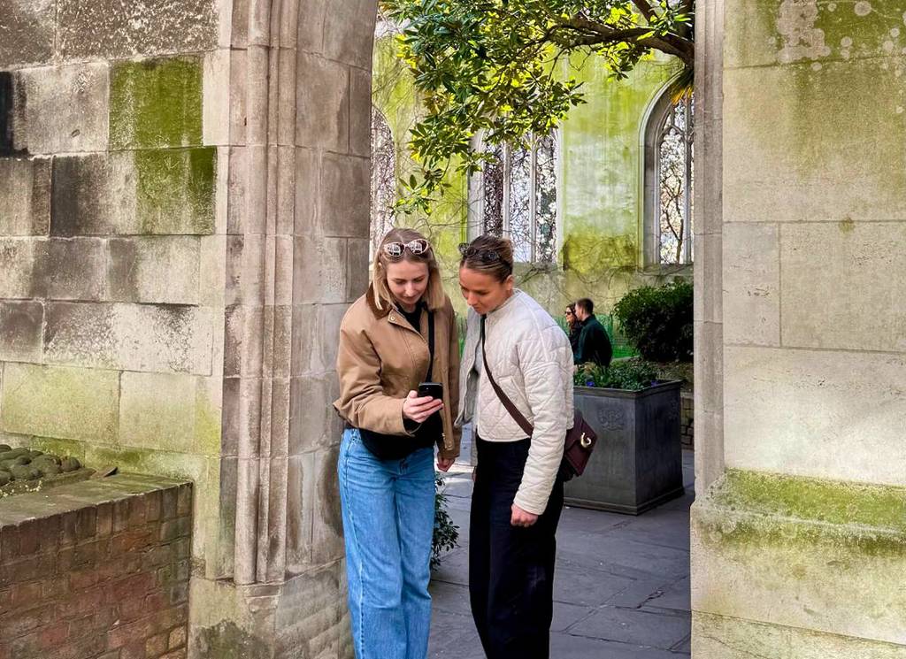 two women look at a phone in St. Dunstan in the East