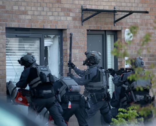 Police officers breaking down a door.