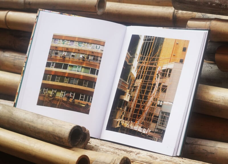 An open book showing two photos of urban buildings, placed on a surface made of stacked bamboo poles.