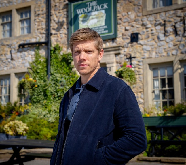 Robert Sugden stands in front of the Woolpack in Emmerdale