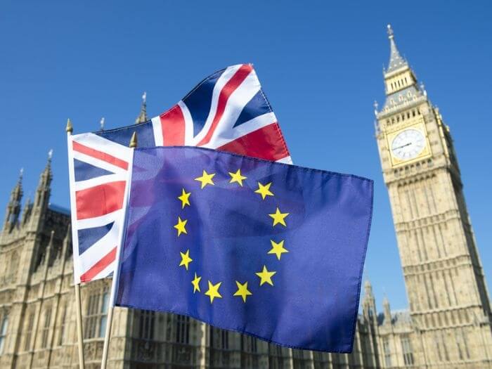 EU and UK flags flying in front of Big Ben and the Houses of Parliament at Westminster Palace, London.