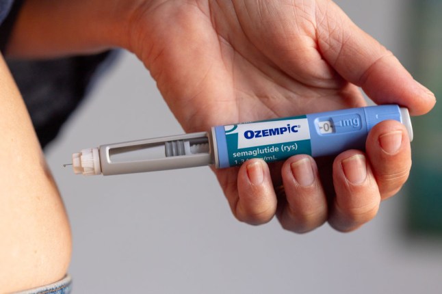 A hand holding an Ozempic injection