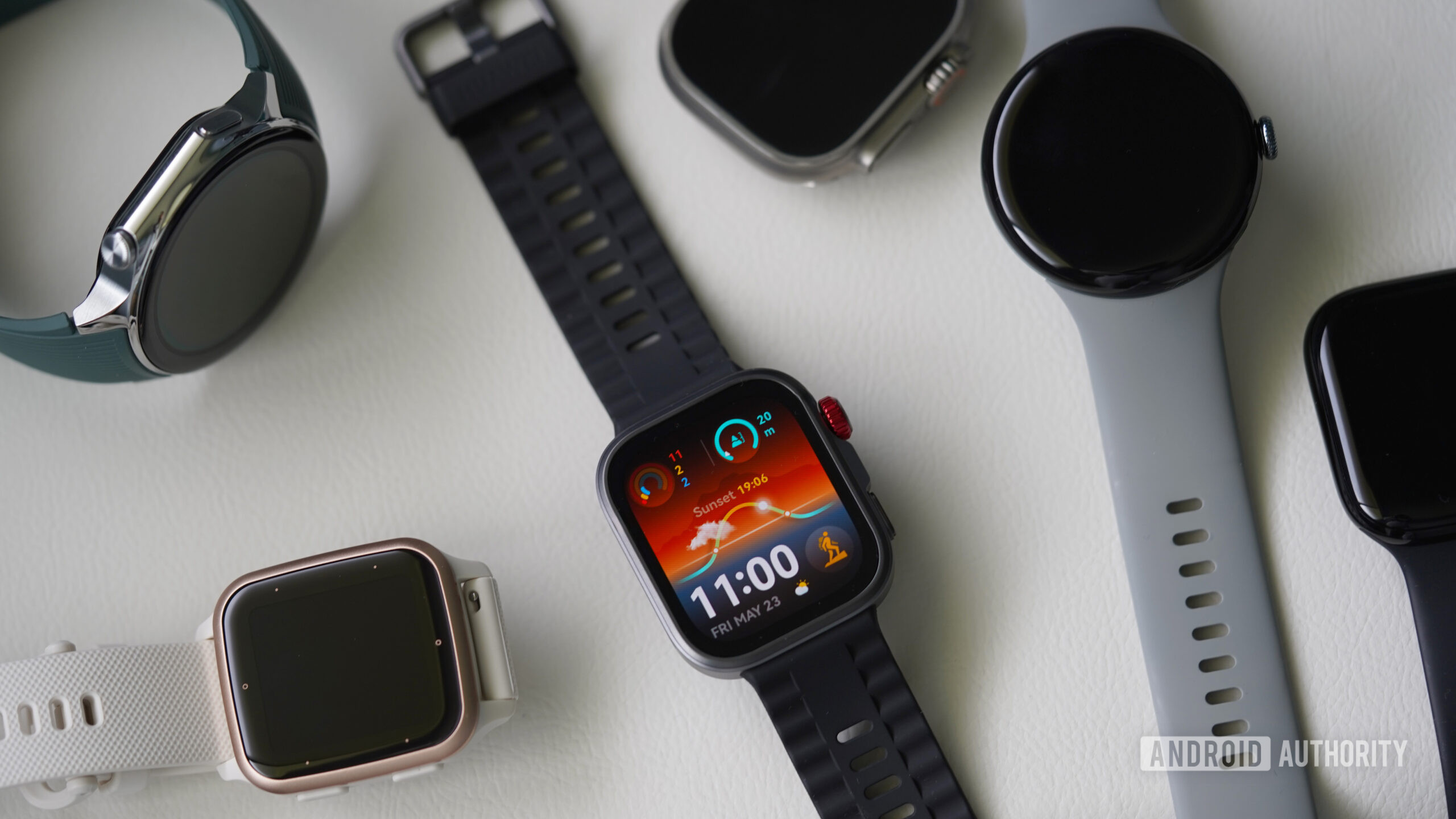 A Huawei Watch Fit 4 Pro rests on a white surface among alternatives.