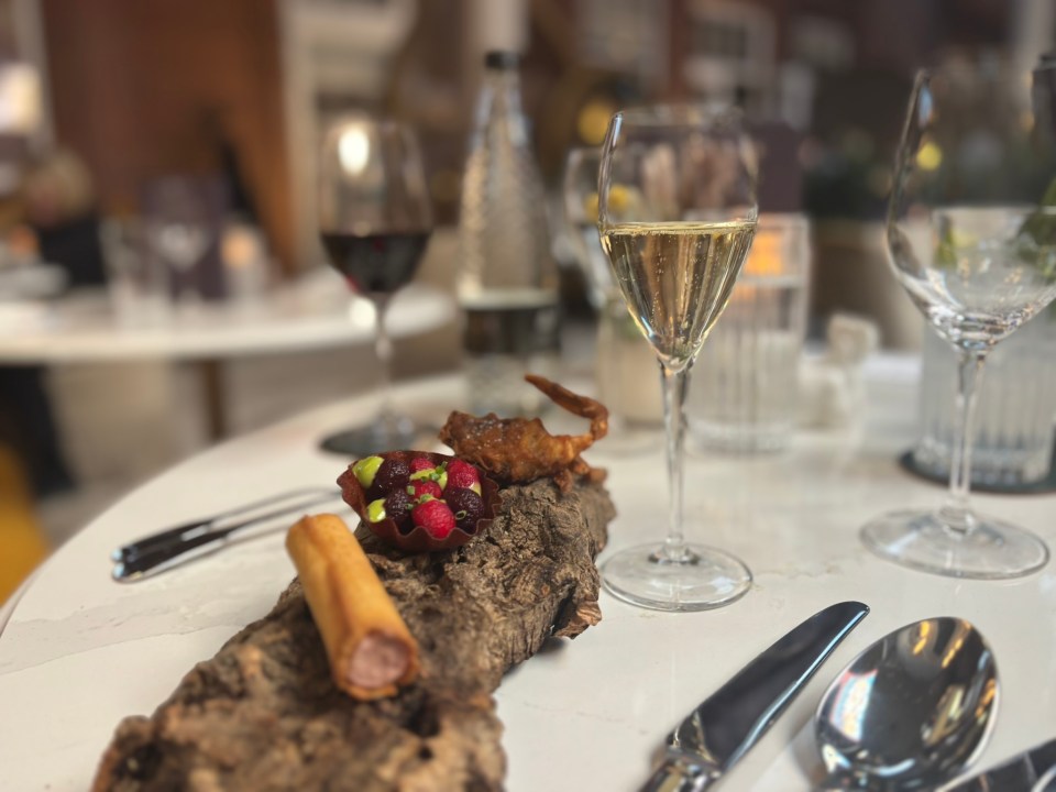Appetizer on a piece of wood with champagne and wine glasses in the background.