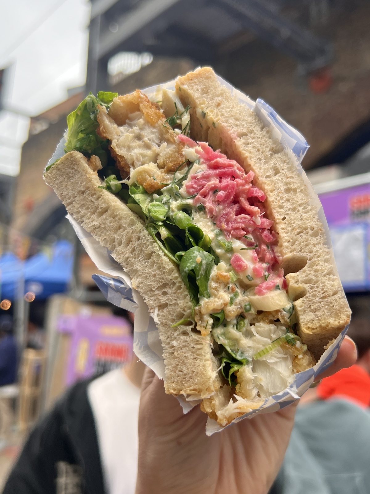 a hand holding up a sandwich for the camera to see the cross-section of a packed sandwich