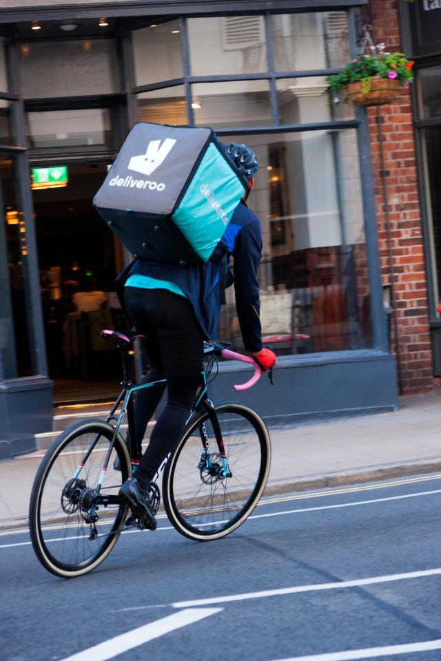 Deliveroo cyclist making a delivery on a bicycle.
