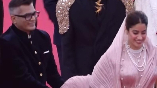 Neeraj Ghaywan holds up Janhvi Kapoor's outfit as she walks the Cannes Film Festival red carpet. 