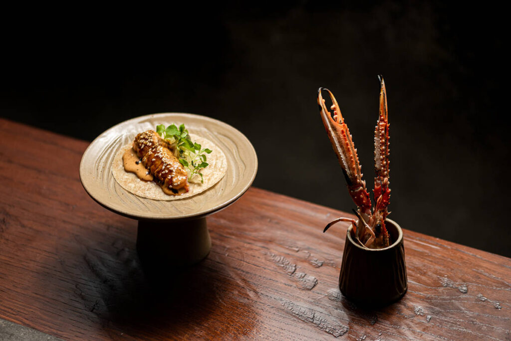 the langoustine taco dish from kol, with a single taco on a special plate, next to a langoustine in a small jug