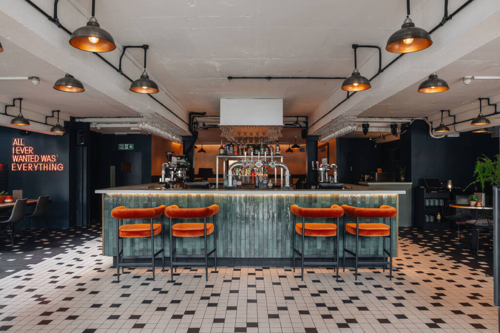An image of the main bar inside Balham's Exhibit wiht orange bar stools and tiled flooring