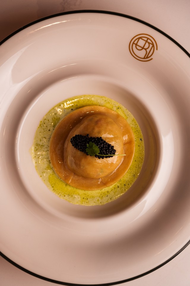 Crab raviolo with caviar and sauce.