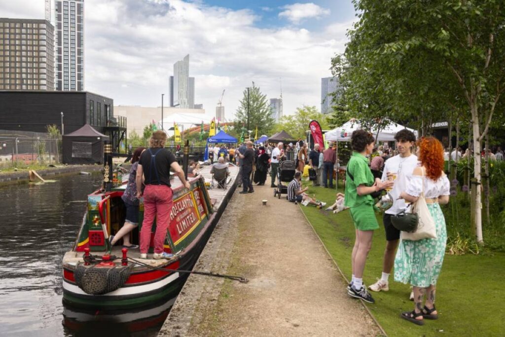 middlewood locks festival people outside next to canal with boat and city in background