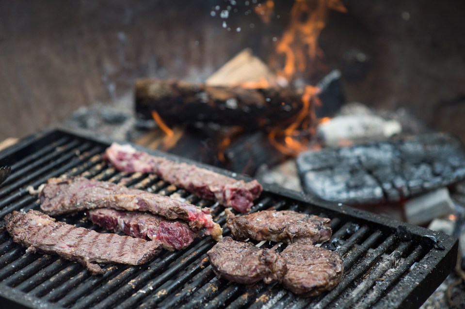 Steaks grilling over an open fire.