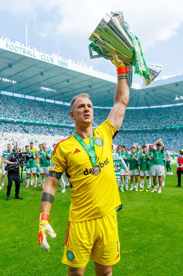Soccer goalie holding aloft a trophy in a stadium.