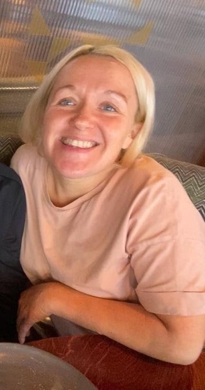 Woman smiling in a peach-colored shirt.