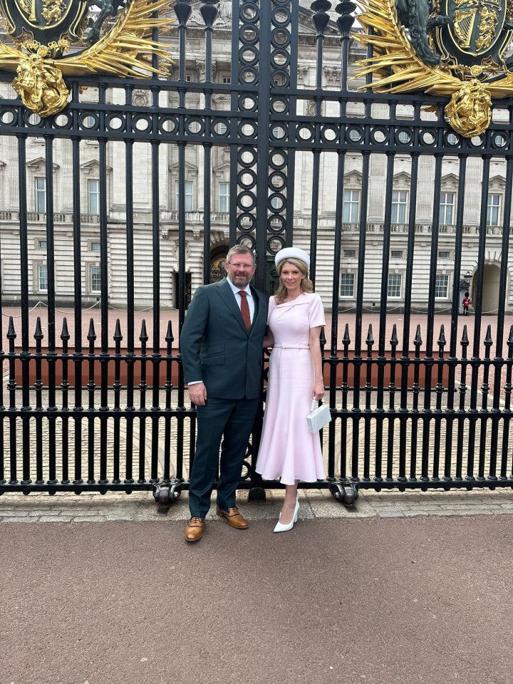 Couple standing in front of Buckingham Palace gates.