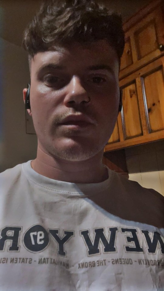 Close-up selfie of a young man wearing earbuds and a New York City t-shirt.