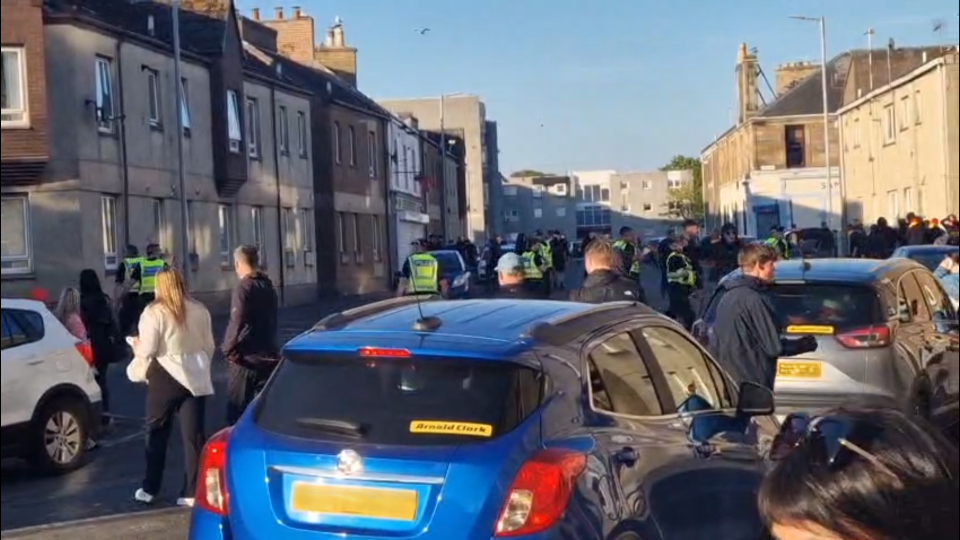 Police officers and bystanders on a residential street.