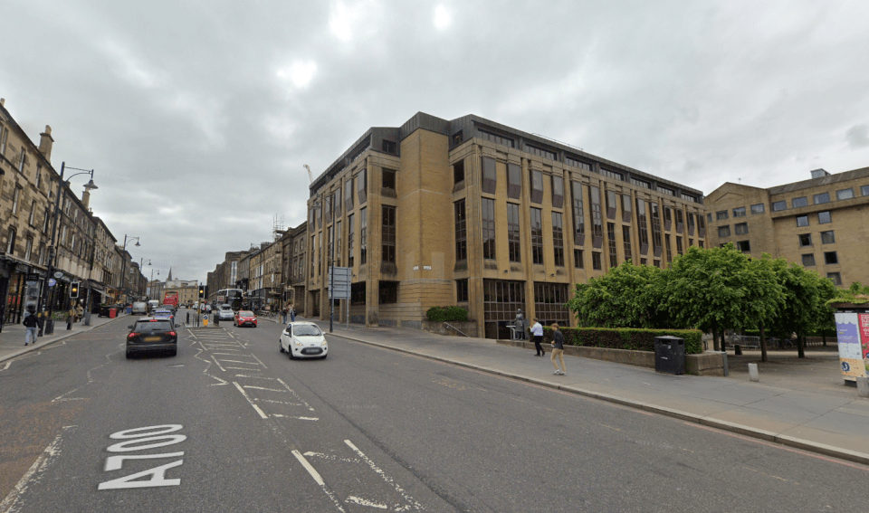 Street view of a city block with cars and pedestrians.