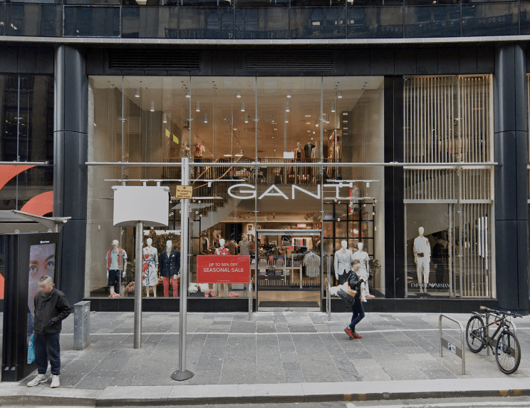 GANT store front with mannequins and seasonal sale sign.