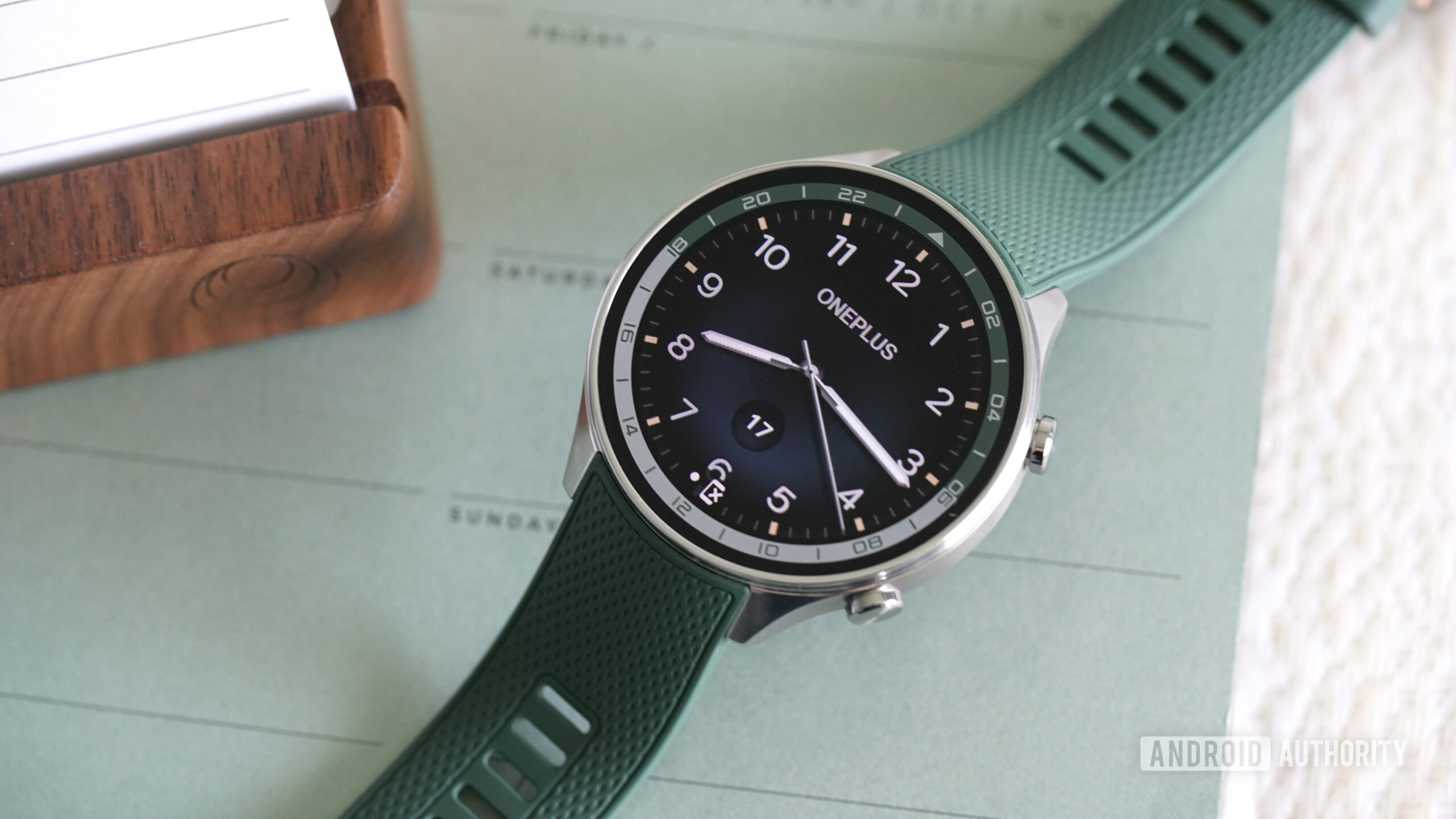 A OnePlus Watch 2R displays a classic watch face.