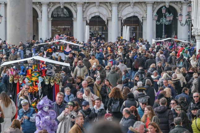A horde of tourists walking in St. Mark's Square near the Doge's Palace in Venice, Italy.