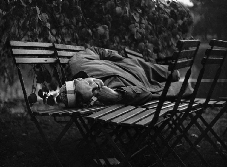 (Original Caption) This Was VE Day In London. The Man who Knew how to Make Himself at Home on the First Night of Peace He has eight chairs instead of a bed. He wears a paper-hat instead of pyjamas. Over his head is a canopy of leaves. All he wants now is to be left alone. So far as we're concerned, he was. (Photo by ?? Hulton-Deutsch Collection/CORBIS/Corbis via Getty Images)