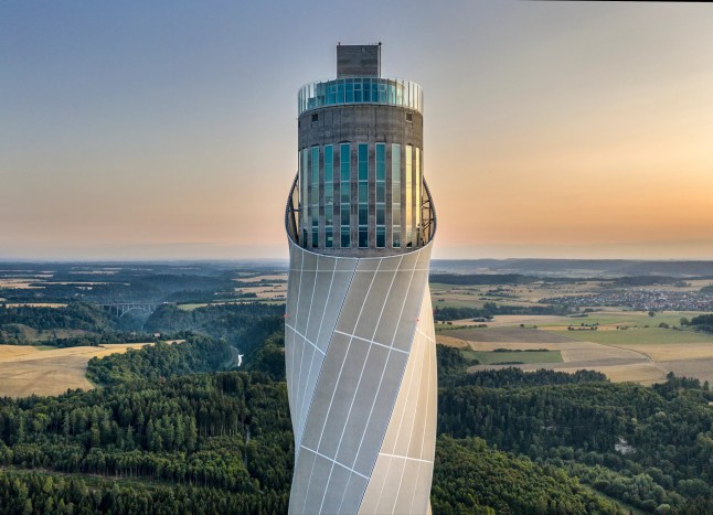 The TK Elevator Testturm tower in Germany, peering above some green forest.