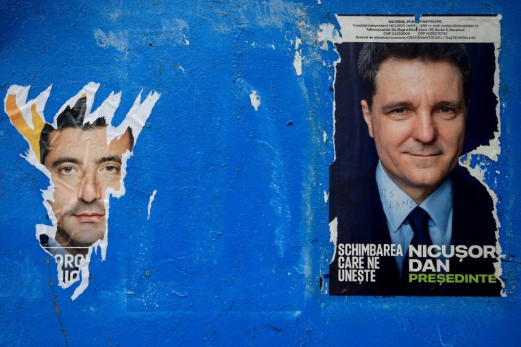 A torn out poster featuring presidential candidate George Simion is seen next to one of Nicusor Dan, with the writing 
